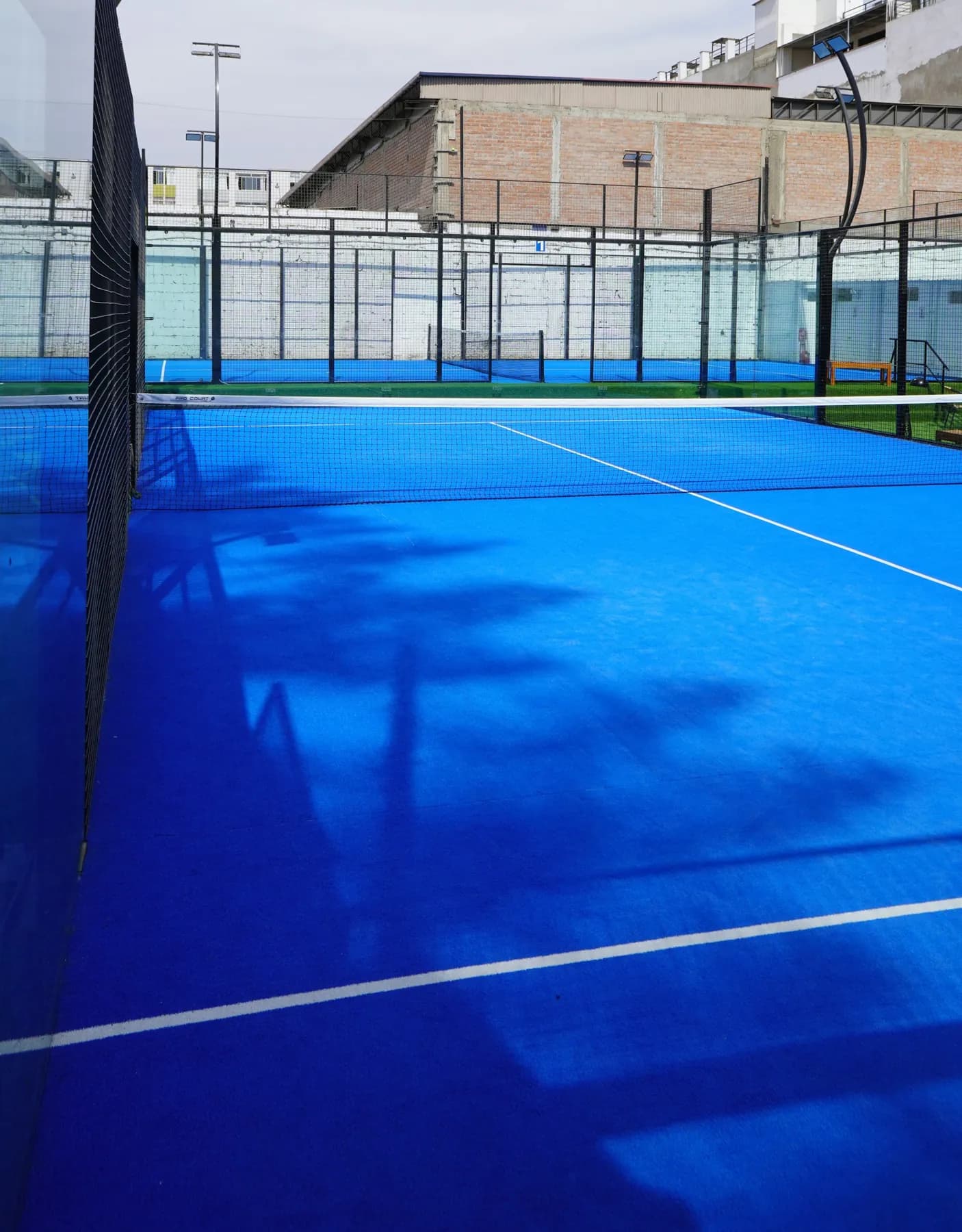 A padel court from the corner, glass wall and floodlights