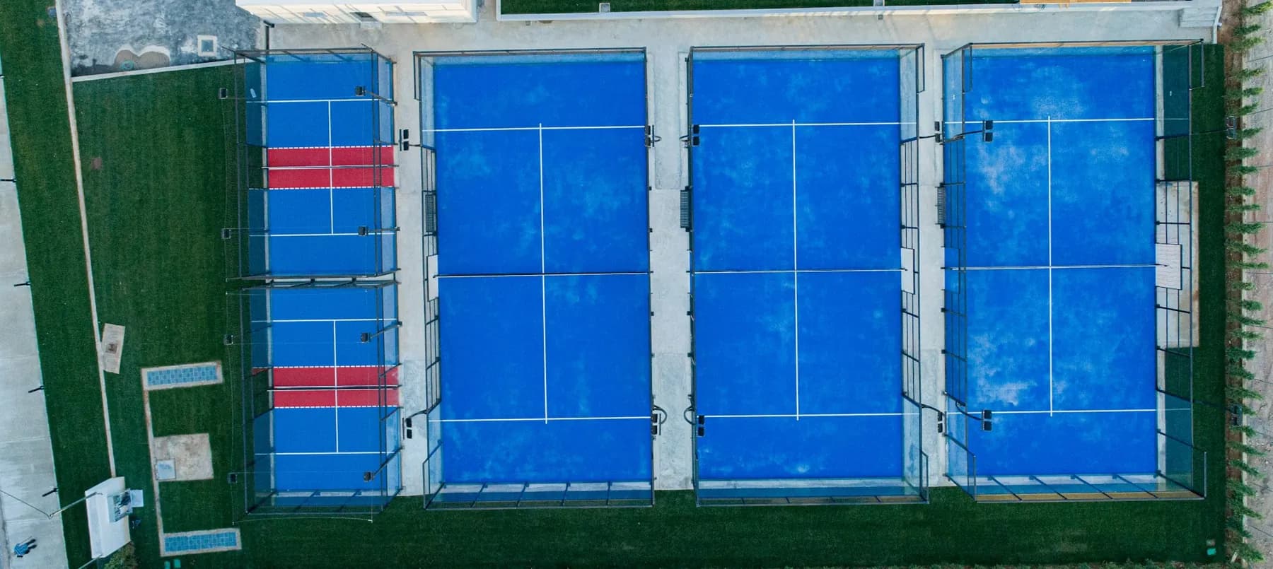 Padel courts from the air, artificial turf surround and red service boxes